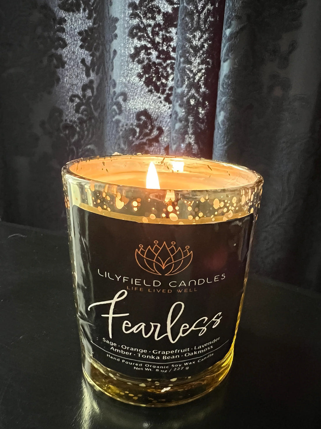 Lit Lilyfield Candles Fearless soy candle in gold-speckled glass on black table