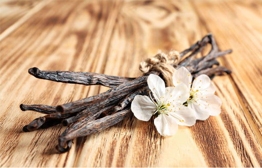 Vanilla beans and white vanilla orchid flowers on rustic wooden table