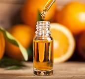 Glass dropper bottle with orange essential oil, fresh oranges in background