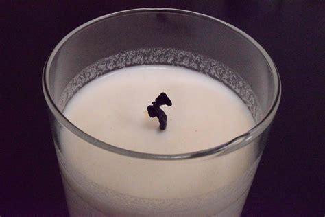 Close-up of a white soy wax candle with a dark wick in a clear glass jar